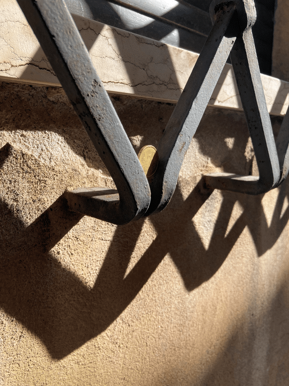 A coin sits in the corner of a window grate.