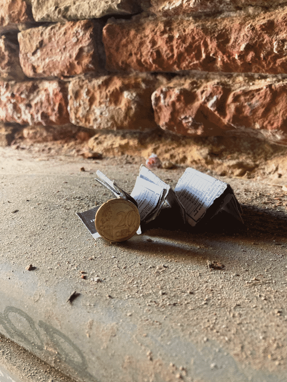 A coin rests against some accordioned paper sitting on a windowsill.