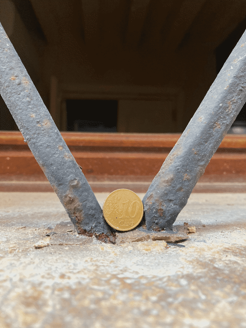 A coin rests at the intersection of two wrought-iron window grate poles.