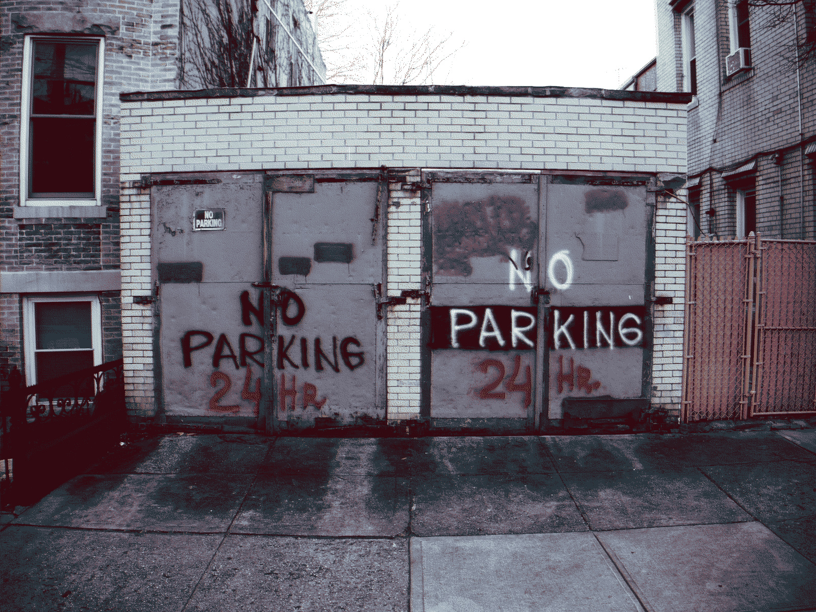 Spray-painted on two adjacent garage doors, in huge letters, NO PARKING 24 HRS.